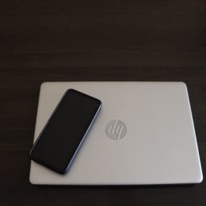 Close-up of a smartphone resting on an HP laptop, symbolizing modern technology integration.